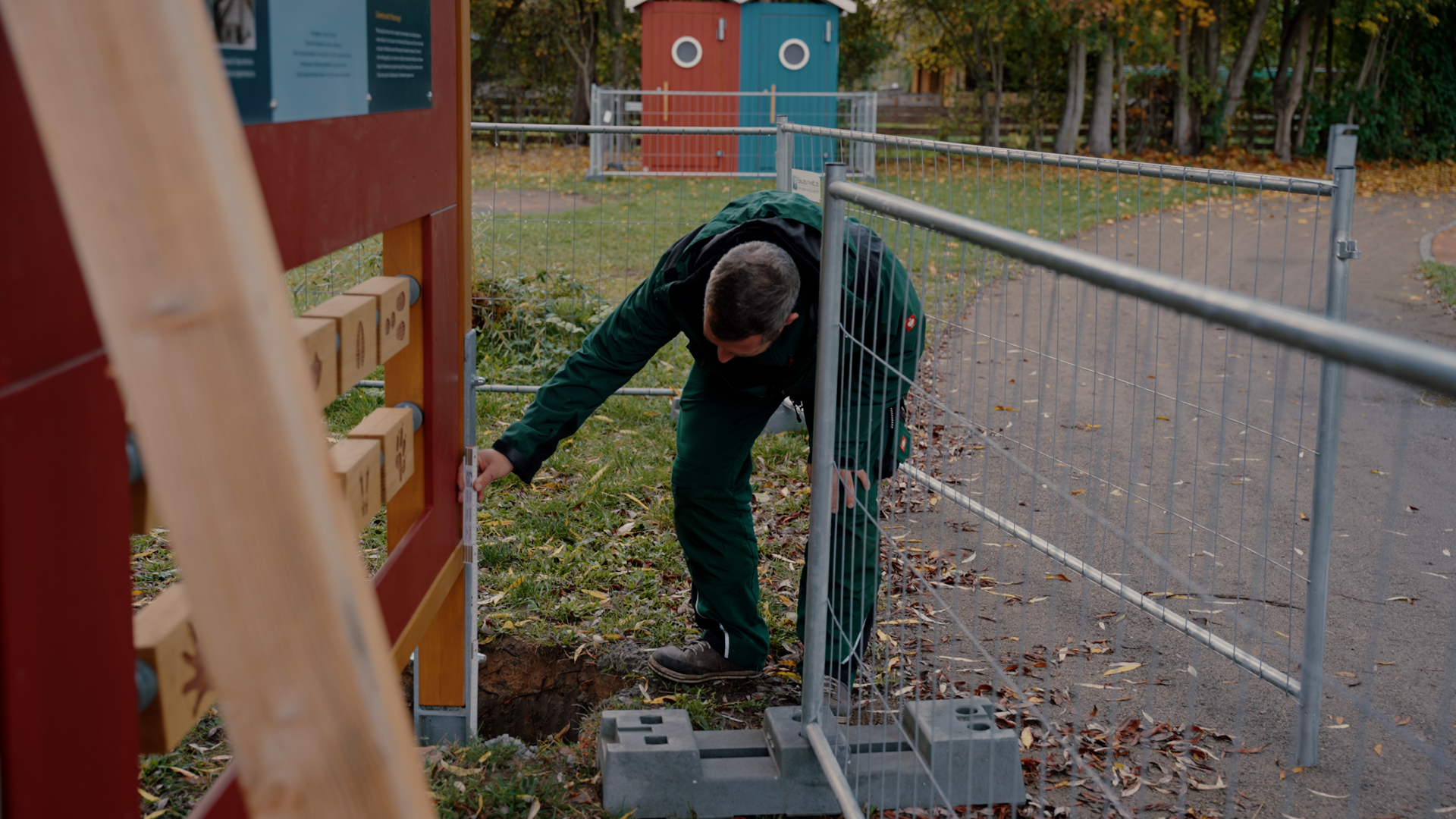 Handwerker in grüner Dienstkleidung misst Balken nach.